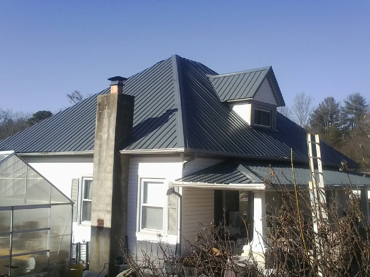 Dark blue standing seam metal roof on a white farmhouse with dormer — Slate & Tile Roof Repair by Roofing Brothers in Imperial