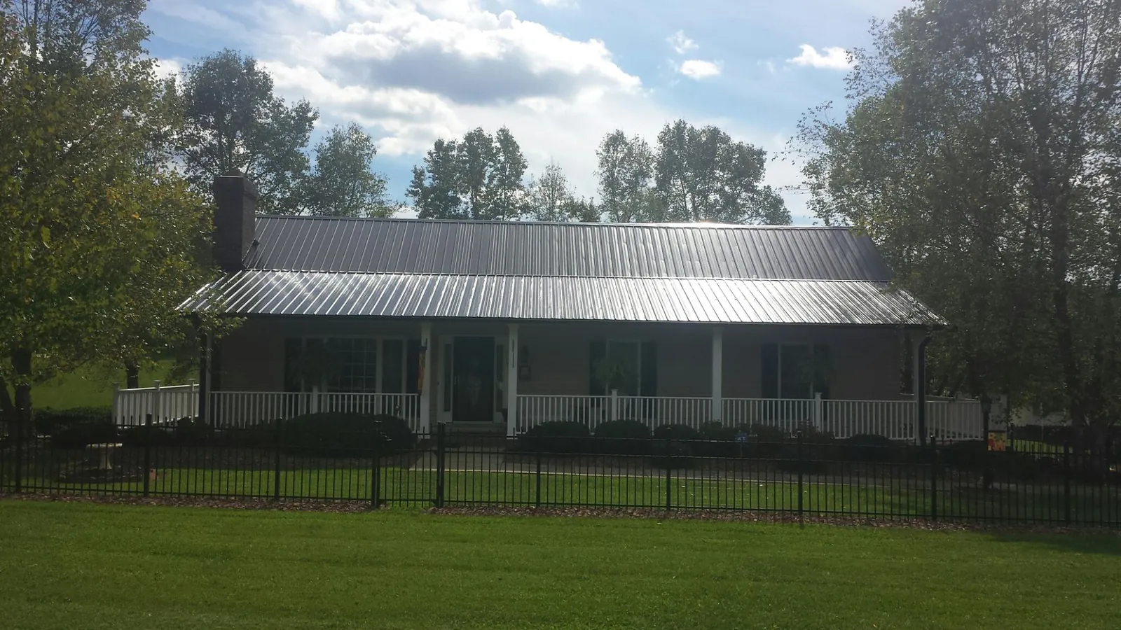 Gray metal roof on a brick ranch with a full width front porch — Gutter Guard Installation work by our crew in Imperial