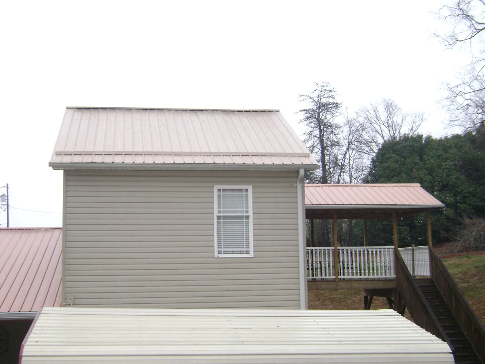 Tan metal roofs on a two story addition and attached porch, from a Roof Replacement job in Imperial
