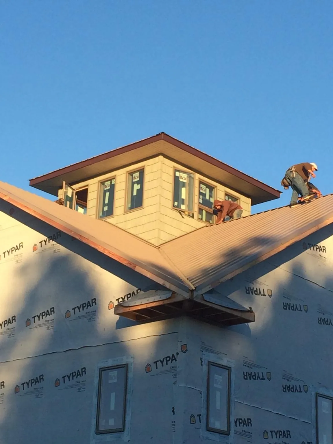 Roofers working around a rooftop cupola on a new metal roof at sunset — Roof Waterproofing in Imperial by Roofing Brothers